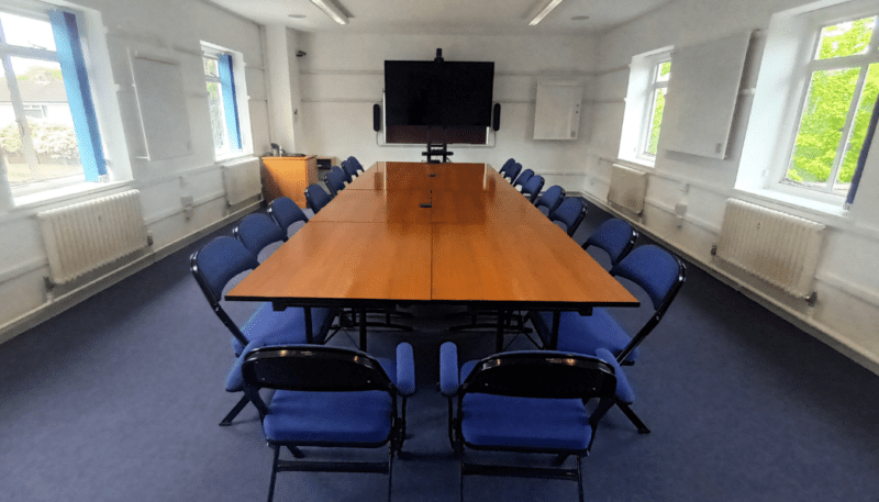 Meeting room on the top floor with a large screen, table and chairs